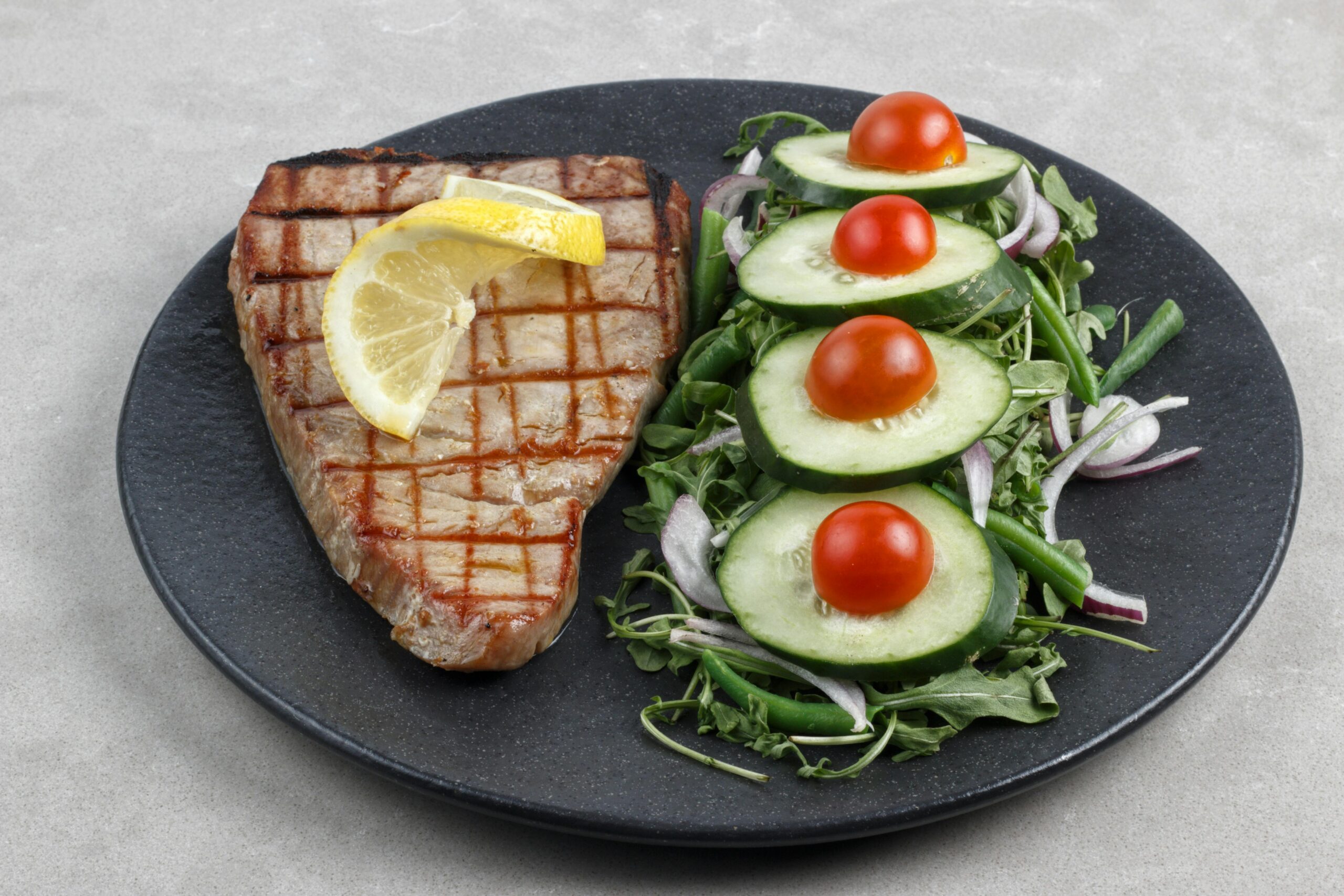 Delicious grilled tuna steak served with fresh cucumber and cherry tomato salad. Perfect for healthy eating.