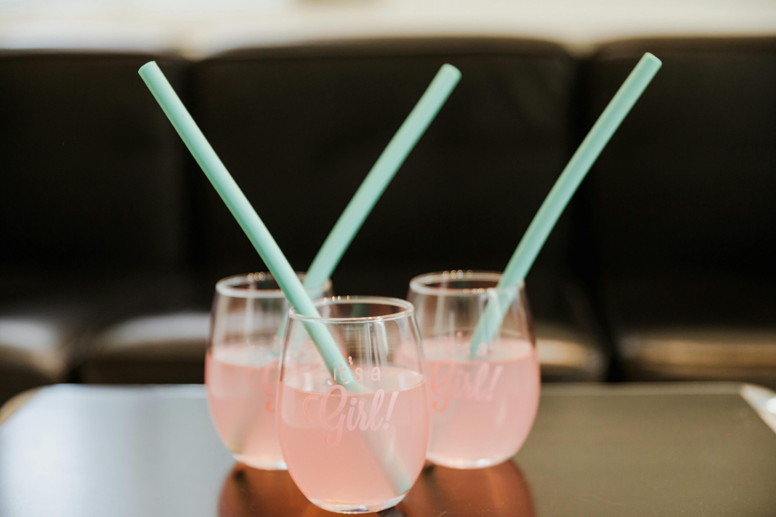 Close-up of pink drinks with turquoise straws in glasses, perfect for celebrations.